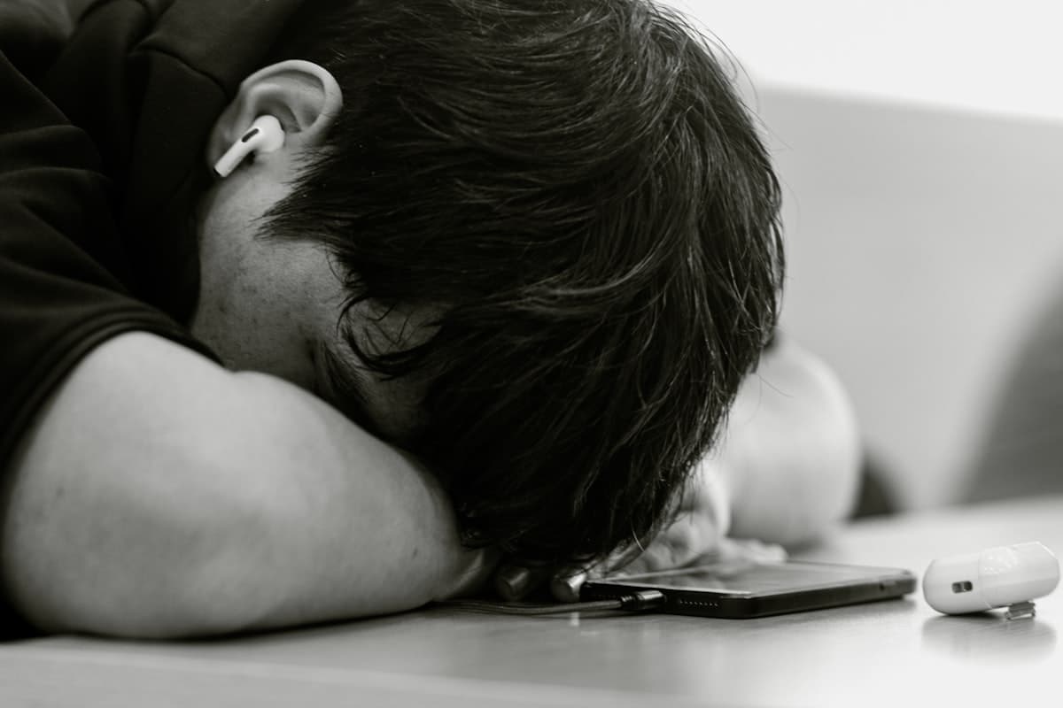 A man resting his head on his phone, exhausted — the picture of financial avoidance