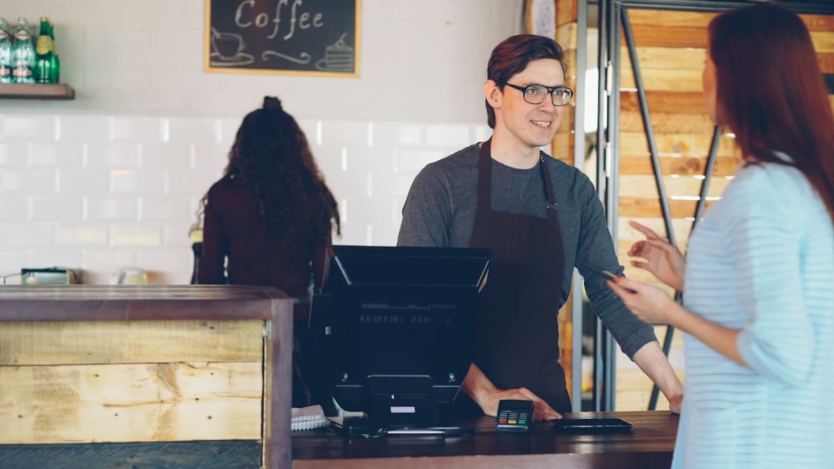 A customer tapping their phone to pay at a coffee shop counter