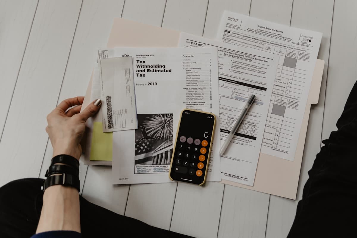 Person reviewing financial papers next to a calculator and pen