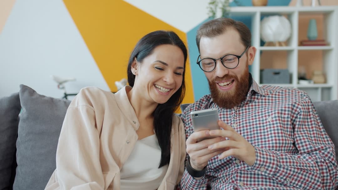Couple laughing while looking at a smartphone together