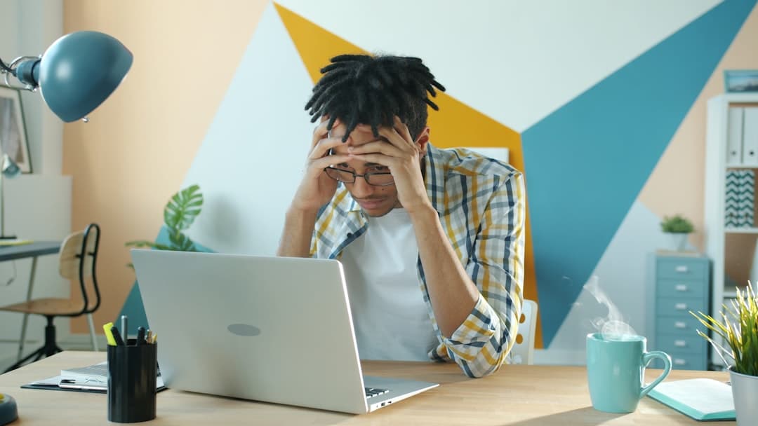 Man holding head in frustration at desk with laptop