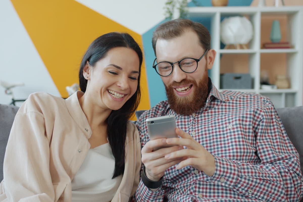 Couple laughing together while looking at a smartphone