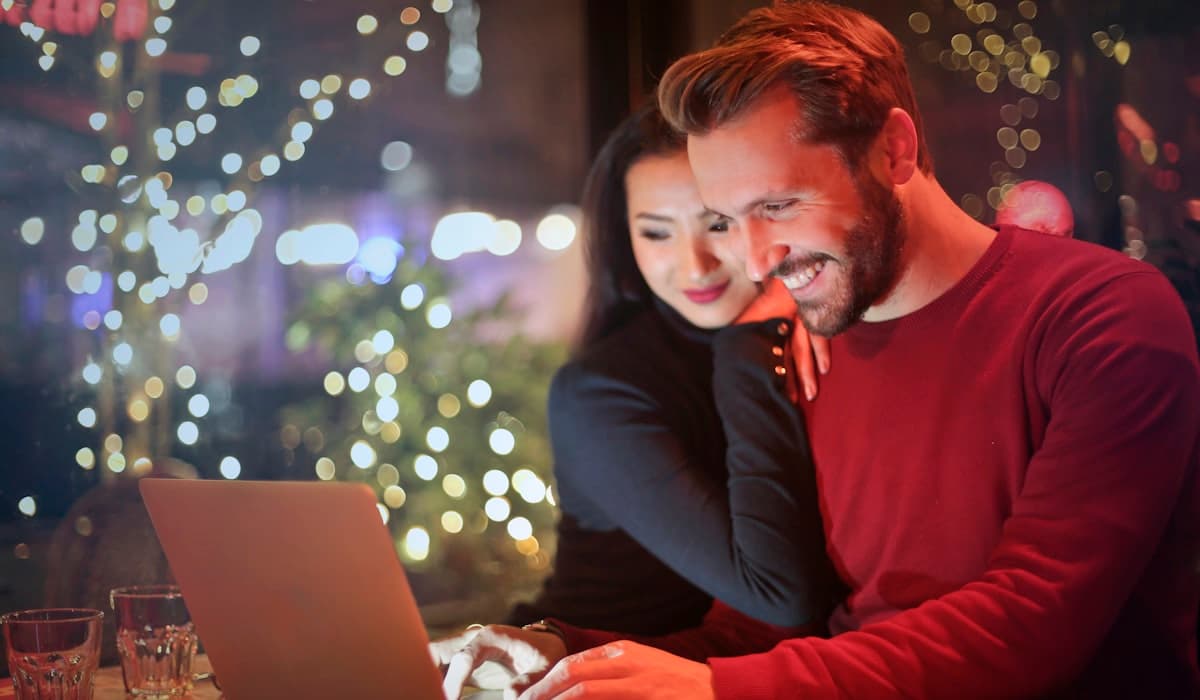 Man and woman looking at a laptop together, both smiling