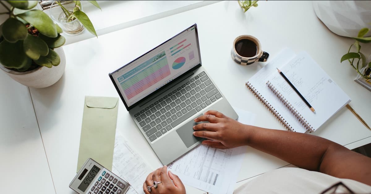 person sitting at a table reviewing finances on a laptop