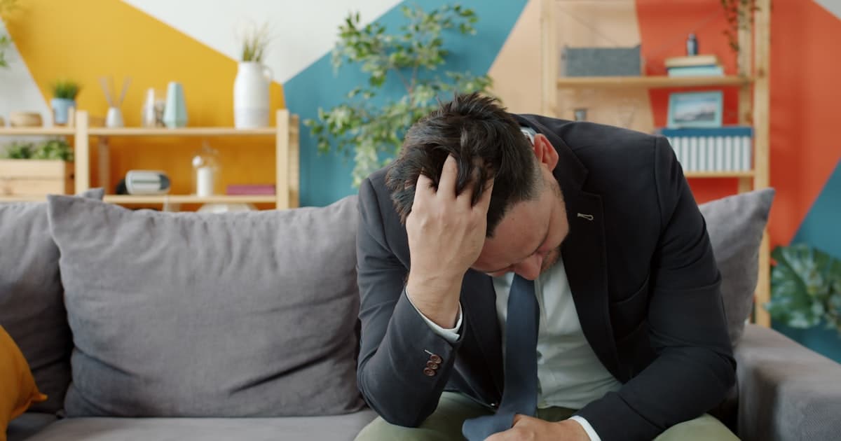 Man in suit sitting on couch with head in hands