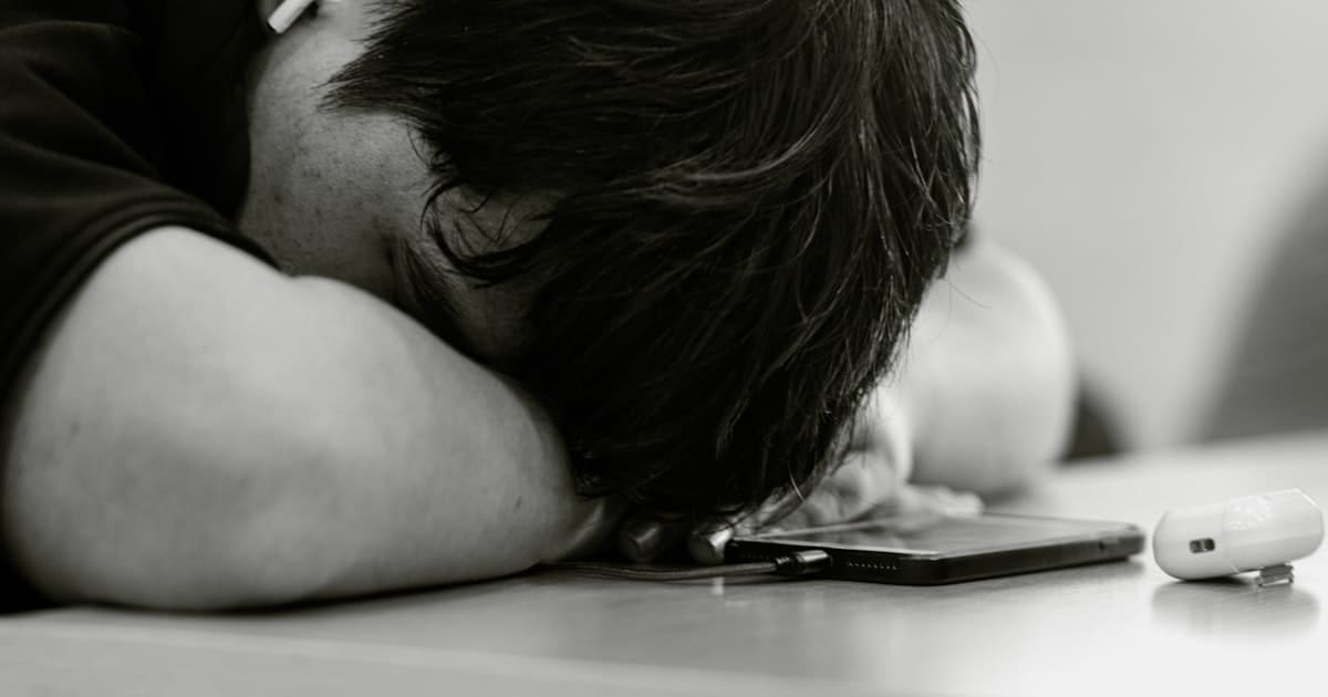 Man resting his head on his phone, looking exhausted and overwhelmed