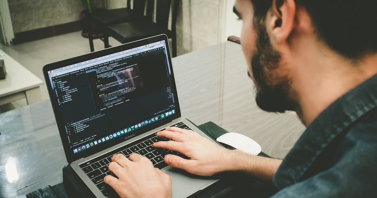 Developer working at a laptop with code visible on screen